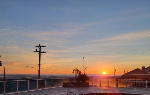 einen Sonnenuntergang über einem Strand mit Meer und einem Zaun in der Unterkunft Champagne Isle Resort Unit 107 in Wildwood
