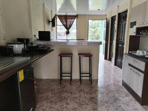 uma cozinha com dois bancos de bar num balcão em Green Line House em Rio Celeste