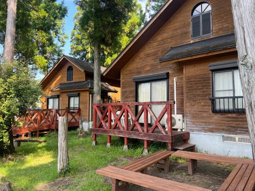 a wooden house with a wooden bridge in front of it at Jisso Youth travel village in Yamano