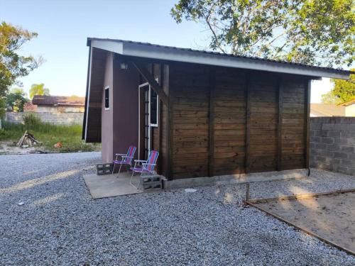 Deux chaises assises à l'extérieur d'une petite maison dans l'établissement Casa - Chalé da praia, à Pontal do Paraná