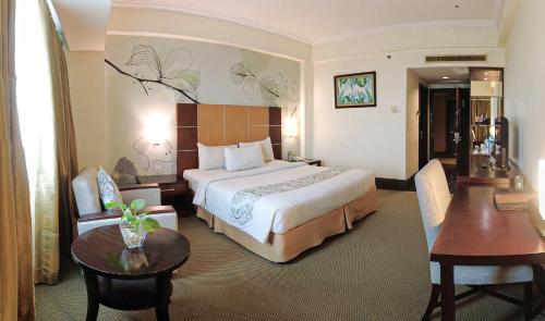 a hotel room with a bed and a table and chairs at Emerald Garden International Hotel in Medan