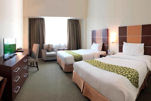 a hotel room with two beds and a television at Emerald Garden International Hotel in Medan