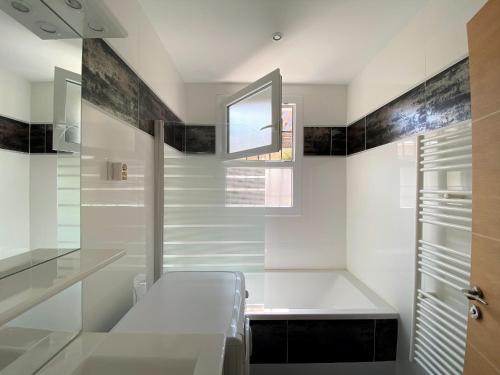 une salle de bains blanche avec un banc et une fenêtre dans l'établissement Spacieux T3 au centre d'Arcachon, 3 étoiles, proche plage et commerces, idéal famille - 5 pers - FR-1-420-111, à Arcachon