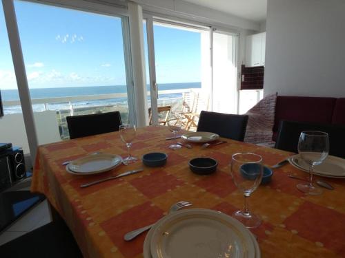 - une table avec des assiettes et des verres et une vue sur l'océan dans l'établissement Notre-Dame-de-Monts - Appartement 58m² avec 2 chambres, parking, balcon - 4 personnes - FR-1-540-243, à Notre-Dame-de-Monts