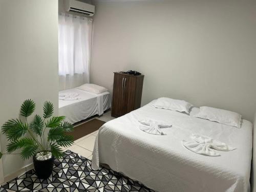 - une chambre avec un lit blanc et une plante dans l'établissement Casa com ótima localização, à Foz do Iguaçu