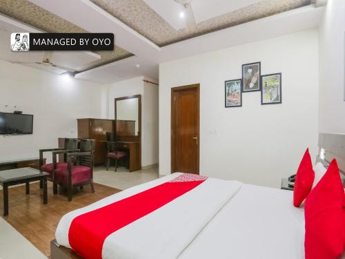 a bedroom with a red and white bed and a desk at Super OYO Chand Palace - Managed by Company in New Delhi