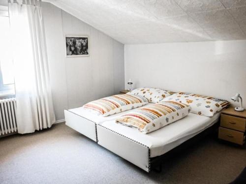 ein weißes Bett mit Kissen darauf im Schlafzimmer in der Unterkunft Chalet Lilo 4 Zimmer big view in Beatenberg