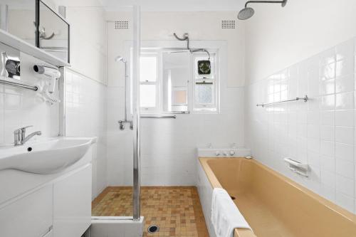 a white bathroom with a tub and a sink at Cozy Lindfield Stayz in Sydney