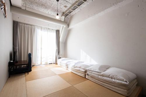 um quarto com uma fila de almofadas brancas no chão em Imano Tokyo Hostel em Tóquio