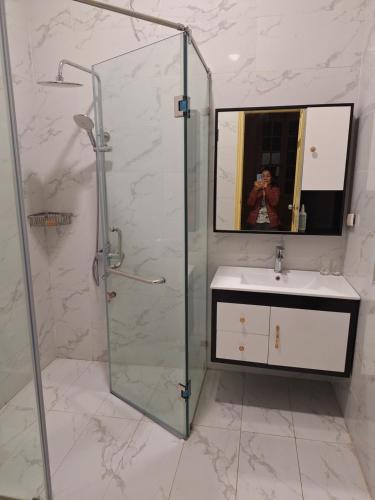 Un baño con ducha, lavabo y espejo. en Green Homestay, en Hanói