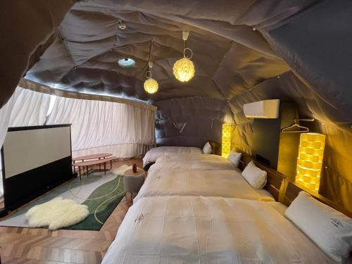 Necoana Glamping Annovillasグランピング في فوجيكاواجوتشيكو: غرفة نوم بسريرين في خيمة