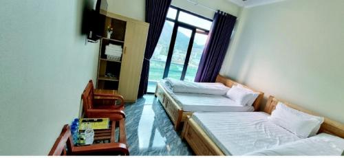 two beds in a room with a window at NHÀ NGHỈ ANH VĂN in Dồng Văn