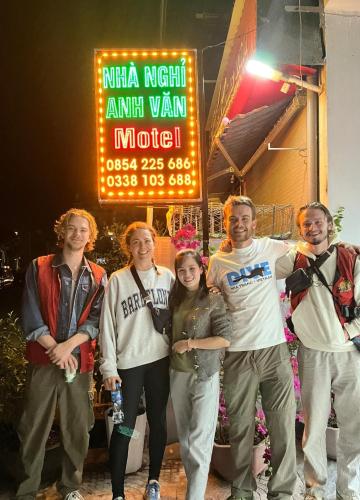 a group of people standing in front of a sign at NHÀ NGHỈ ANH VĂN in Dồng Văn