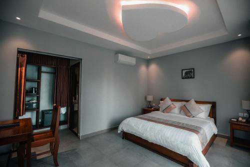 a bedroom with a bed and a table and a desk at Sokchea Kampot Hotel in Kampot