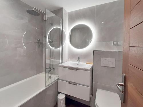La salle de bains est pourvue d'un lavabo et d'une douche avec deux miroirs. dans l'établissement Studio Rénové 3p · Pied des Pistes · Balcon Sud/Ouest · 3 Flocons Or - FR-1-344-1206, aux Menuires