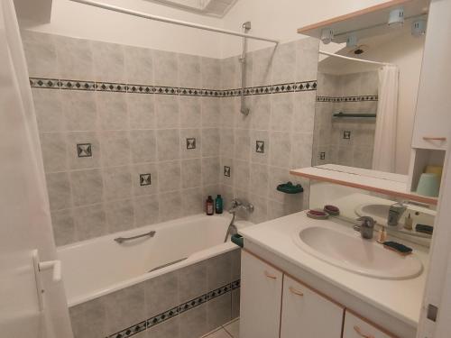 une salle de bain avec une baignoire et un lavabo et une baignoire dans l'établissement Duplex confortable au cadre verdoyant avec piscine, proche du golf - FR-1-323-493, à Saint-Jean-de-Monts