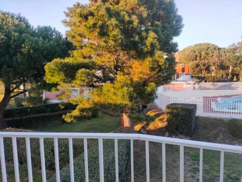 une clôture blanche devant une cour avec un arbre dans l'établissement Duplex confortable au cadre verdoyant avec piscine, proche du golf - FR-1-323-493, à Saint-Jean-de-Monts