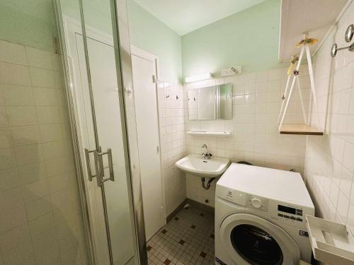 une petite salle de bains avec un lave-linge et un lavabo dans l'établissement Fouesnant, 50m plage Cap Coz, app. cosy 2 pers, terrasse, parking - FR-1-481-154, à Fouesnant