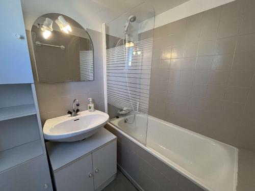 ein Badezimmer mit einem Waschbecken, einer Badewanne und einem Spiegel in der Unterkunft Appartement Marseillan-Plage, 2 pièces, 6 personnes - FR-1-387-201 in Marseillan
