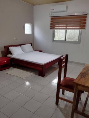 a bedroom with a bed and a table and a chair at Residence Mindja in Kribi