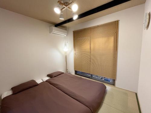 芙蓉居 日本庭園付き一戸建 【天下茶屋から徒歩8分】最大6名宿泊可能 في أوساكا: غرفة نوم صغيرة بها سرير ونافذة