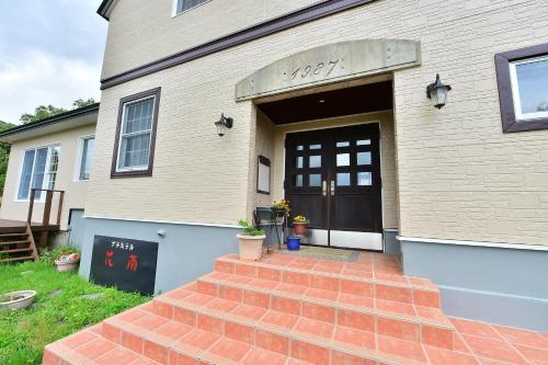 une maison avec un escalier en briques menant à une porte dans l'établissement Petit Hotel Kanan, à Chino