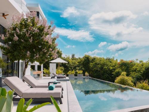 a swimming pool with lounge chairs and a villa at Casa Alma by Elite Havens in Nai Harn Beach