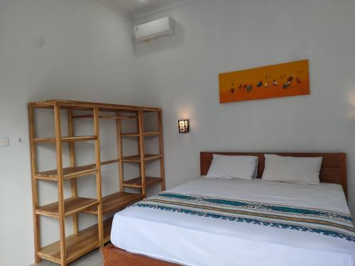 een slaapkamer met een bed en een boekenplank bij Vera Koe in Kuta Lombok