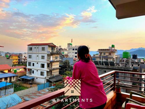 a woman sitting on a balcony looking at the city at Nishan Apartments -Lakeside in Pokhara