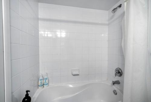 a white bathroom with a bath tub with a shower at Toronto downtown Fort York suites 1BDRM with parking in Toronto