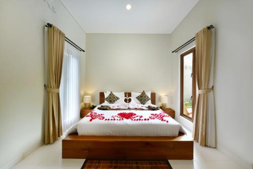 a bedroom with a bed with red flowers on it at Mahayoga Ubud Private Pool Villa And Spa in Ubud