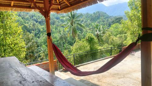 a hammock on a house with a view of the forest at Buda's Homestay Lemukih in Buleleng