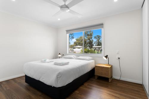 a white bedroom with a large bed and a window at Waikerie Holiday Park in Waikerie