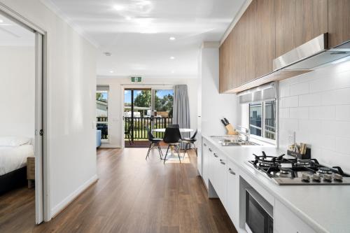 a kitchen with white cabinets and a stove top oven at Echo Holiday Parks - Waikerie in Waikerie