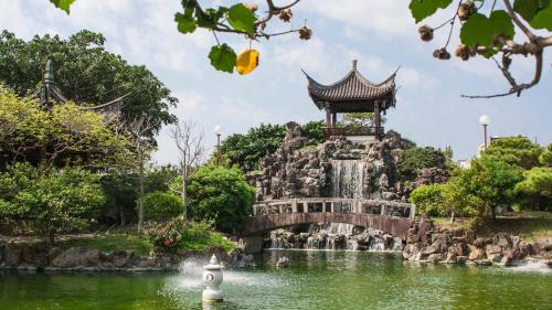 a fountain in a pond in a park with a pagoda at Toyoko Inn Okinawa Naha Asahibashi Ekimae in Naha
