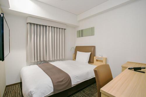 a small room with a bed and a table at Mars Garden Hotel Hakata in Fukuoka