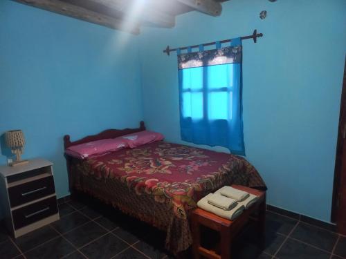 Dormitorio azul con cama y ventana en Casa de familia en Cachí