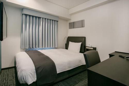 a hotel room with a bed and a desk at Mars Garden Hotel Hakata in Fukuoka