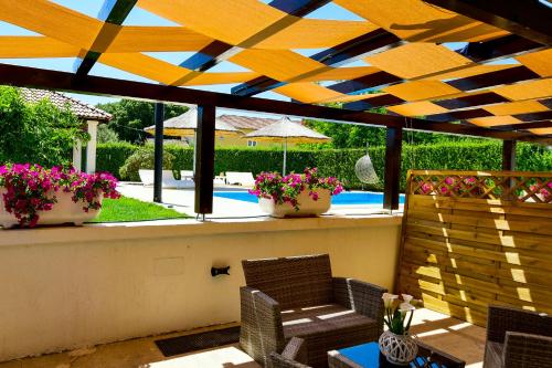 eine Terrasse mit 2 Stühlen, einem Sonnenschirm und Blumen in der Unterkunft Bliss Residences Biograd Apartments - Happy Rentals in Biograd na Moru