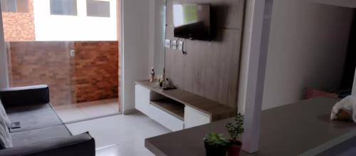 ein Wohnzimmer mit einem TV und einem Badezimmer in der Unterkunft Apto familiar c/ piscina, próx as praias reg Sul in João Pessoa