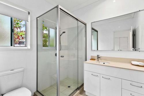 a white bathroom with a shower and a sink at Beachfront Nirvana in Urangan