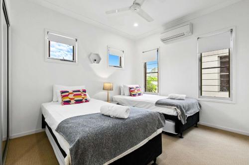 two beds in a room with two windows at Beachfront Nirvana in Urangan