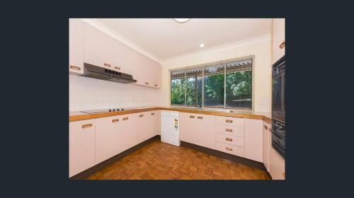 a kitchen with white cabinets and a large window at Brisbane Traveler's nature home in Moggill