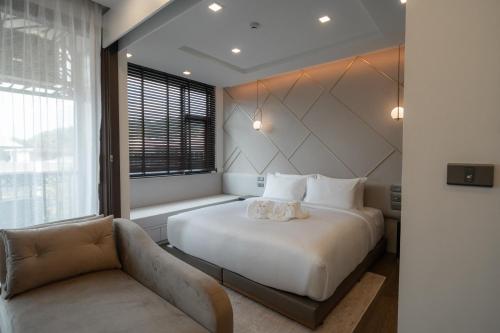 a bedroom with a white bed and a couch at The Proud Karon Beach Phuket Trademark Collection By Wyndham in Karon Beach