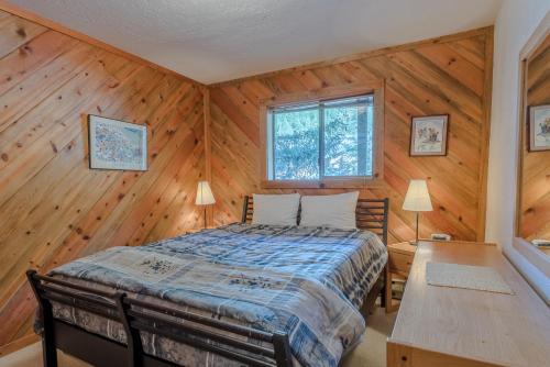 - une chambre avec un lit dans une pièce dotée de murs en bois dans l'établissement Smokey Plaza Condo 1 - Just Blocks from Bald Mountain & Hot Tub Onsite, à Ketchum
