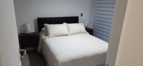 1 dormitorio con 1 cama con sábanas y almohadas blancas en Departamento Coquimbo, en Coquimbo