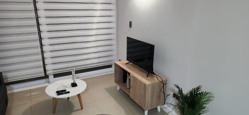 sala de estar con TV, mesa y chimenea en Departamento Coquimbo, en Coquimbo