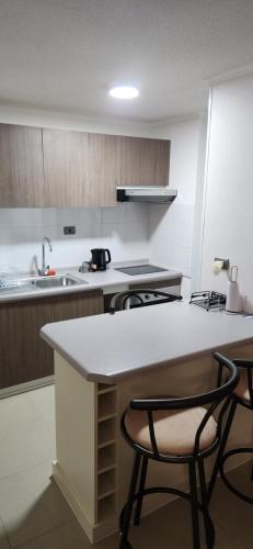 una cocina con encimera y algunas sillas. en Departamento Coquimbo, en Coquimbo