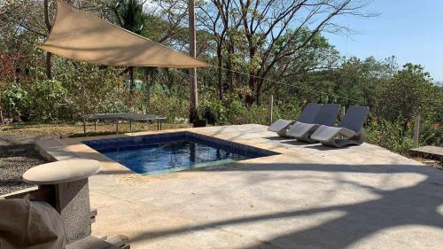 a swimming pool with two chairs and a table at Container home 25 min Jaco y Herradura in Tarcoles