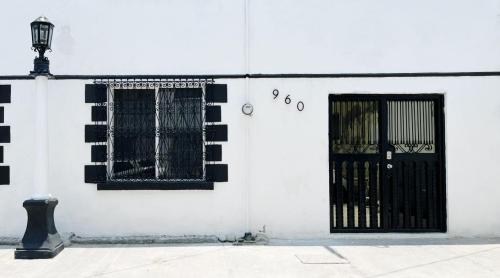 un edificio blanco con una puerta y ventanas negras en Confortable Loft MN 960 E Centro Mty cerca de todo, en Monterrey
